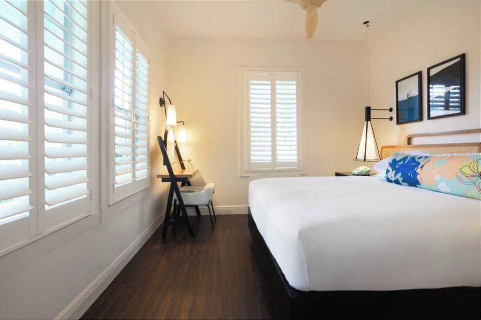 Unwind in a sunlit room with desk and calming shutters.