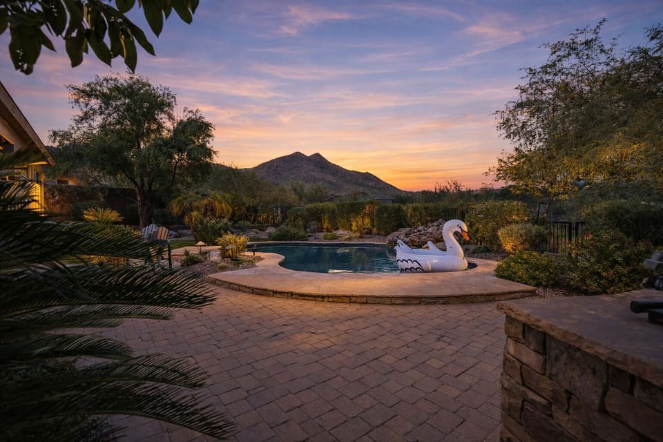 Beautiful backyard with a covered patio, sparkling pool, shaded seating, dining area, grill, and grass area.