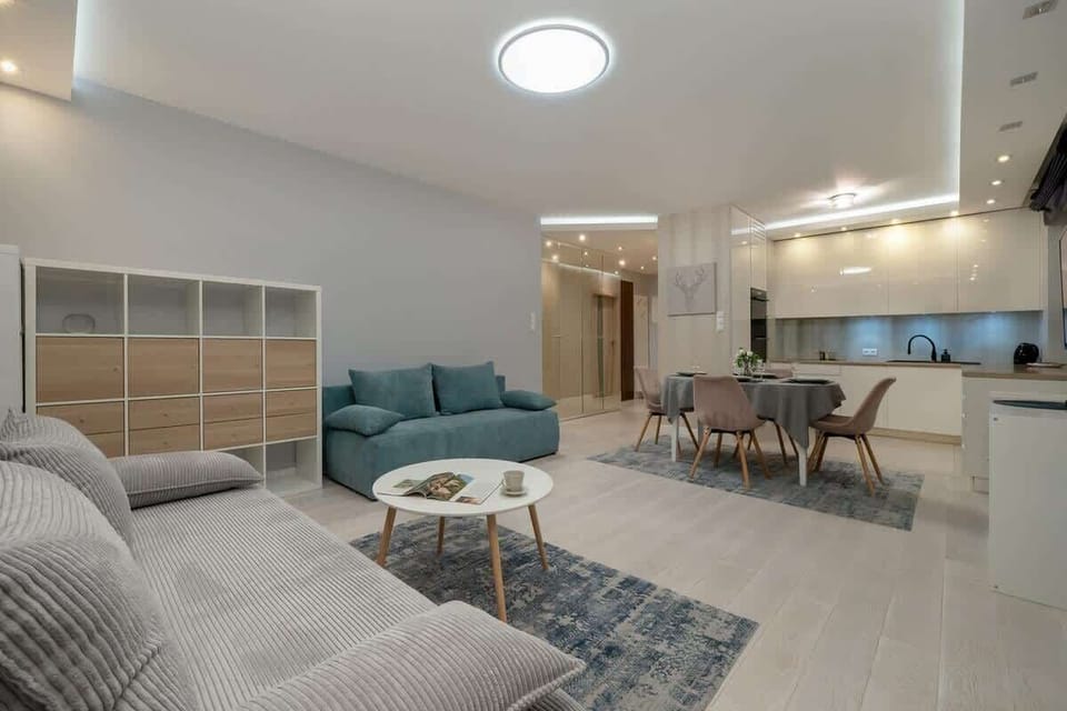 Spacious living room with sofas, blue curtains, and a round white coffee table.