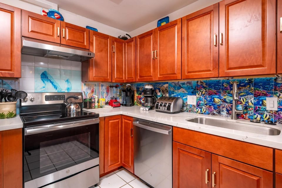 Warm wood cabinetry and tropical backsplash make this your perfect Maui cooking retreat. MAH-1219