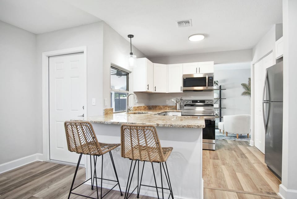 Modern kitchen with granite island, bar stools & stainless appliances