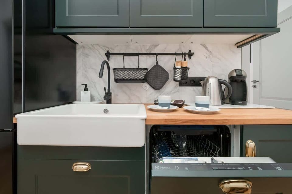 Another angle of the dark green kitchen cabinets and white farmhouse sink, highlighting the elegant gold handles.