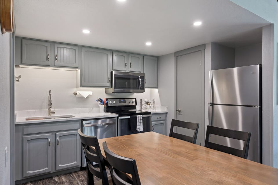 Well-equipped kitchen with stainless steel appliances, ample cabinet storage, and a dining table—ideal for preparing meals and enjoying time together.