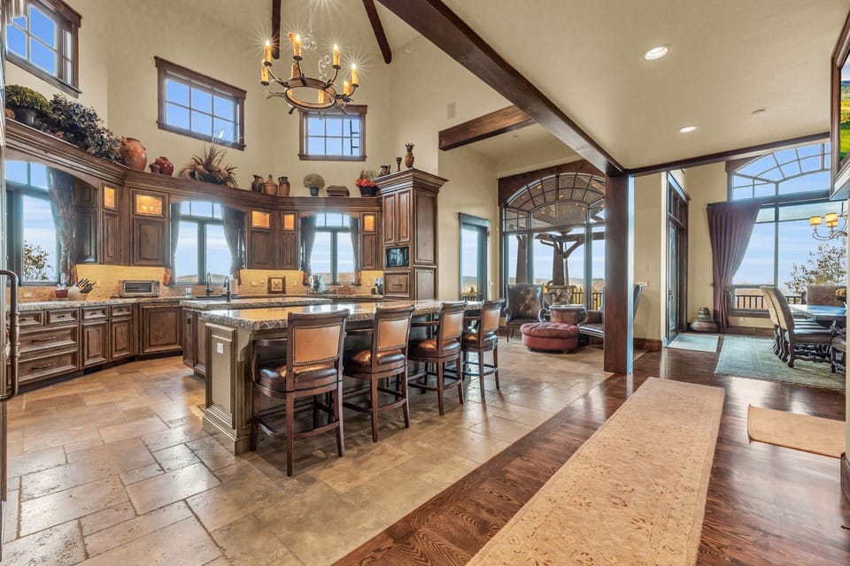 Gourmet kitchen with stone counters and dining room fitted with chandelier.