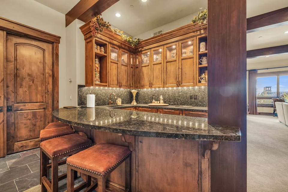 Bar at Morning Star luxury vacation rentals, four stools, marble counter, wooden shelves.