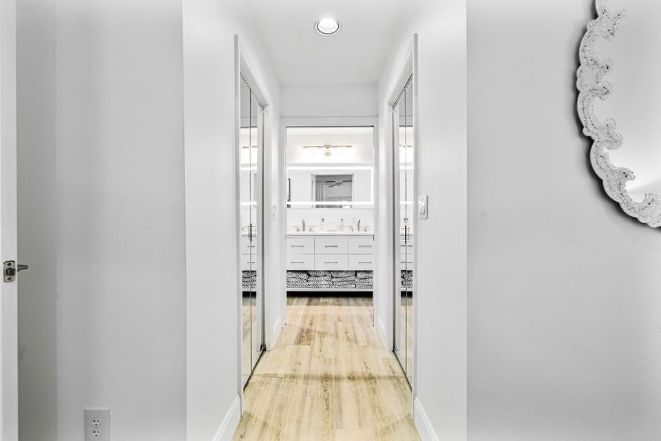 Primary bed hallway to bathroom large walk-in mirror door closets on each side