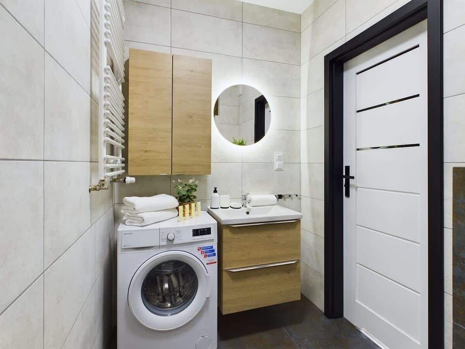 Stylish bathroom with a walk-in shower, washing machine, and wooden accents.