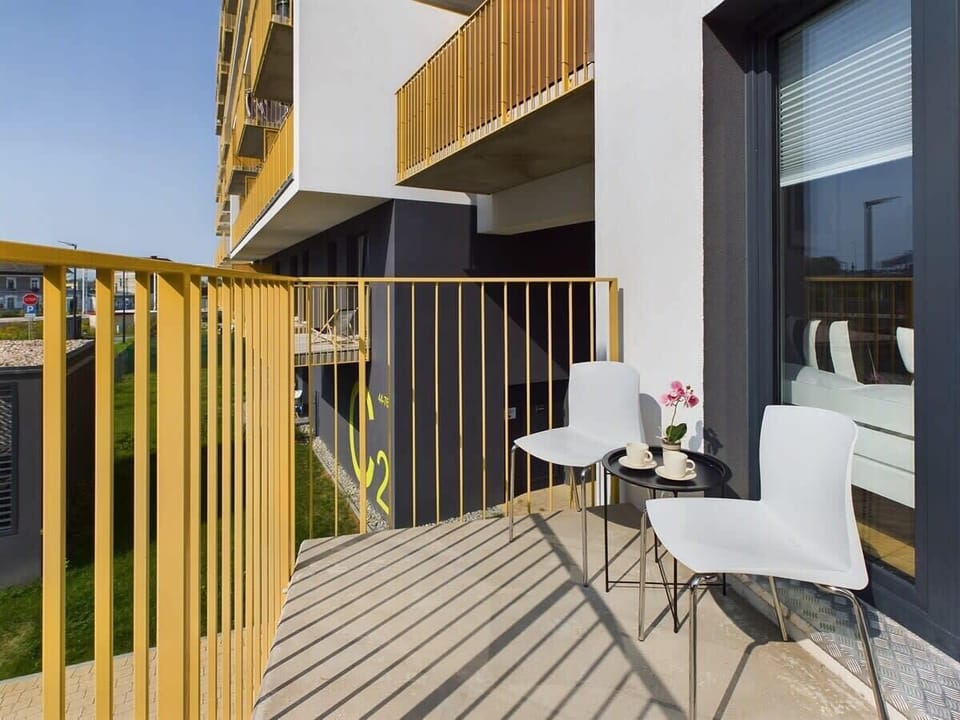 Private balcony with outdoor seating and a table, surrounded by modern railing design.