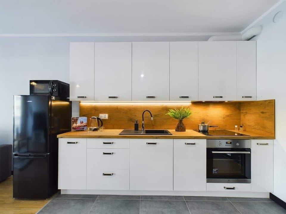 A compact, modern kitchen with white cabinets and wooden countertops.