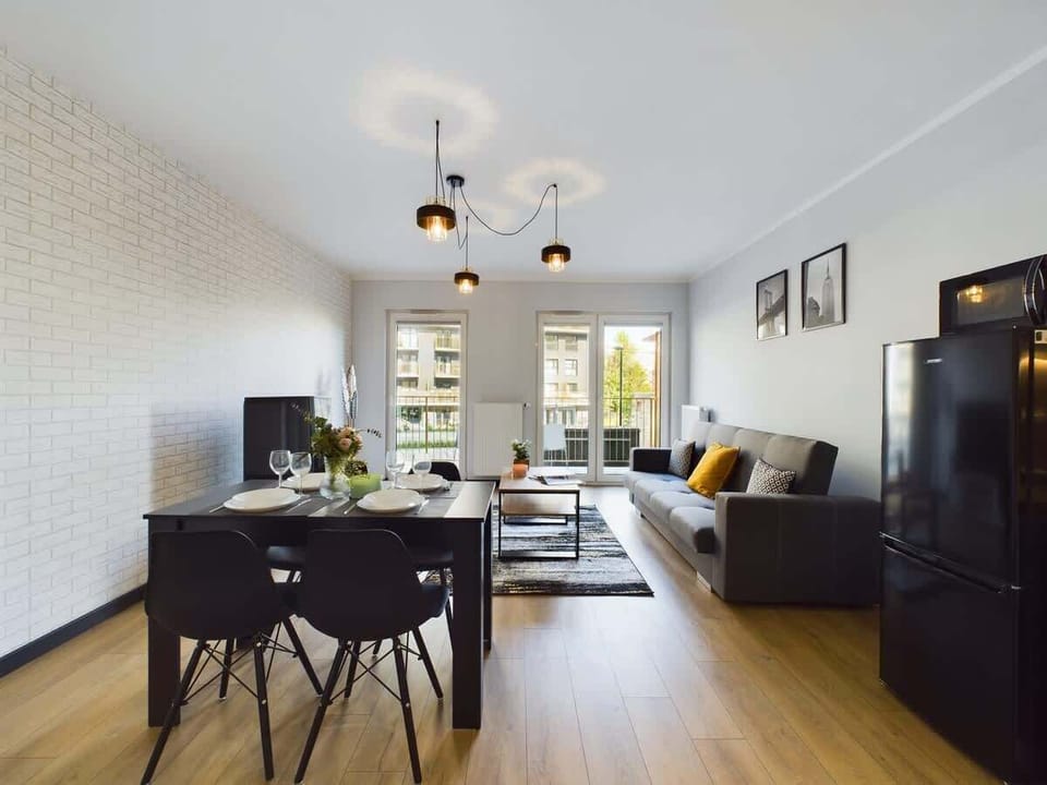 A comfy, well-lit living room with a gray couch, yellow accents, and wall art.
