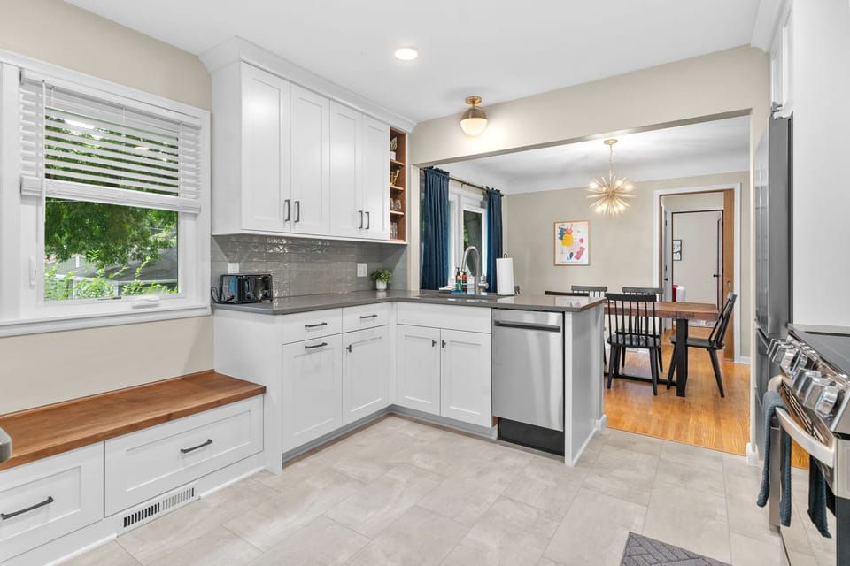Your fully equipped kitchen features crisp white cabinets, modern appliances, and a cozy window seat where you can sip morning coffee.