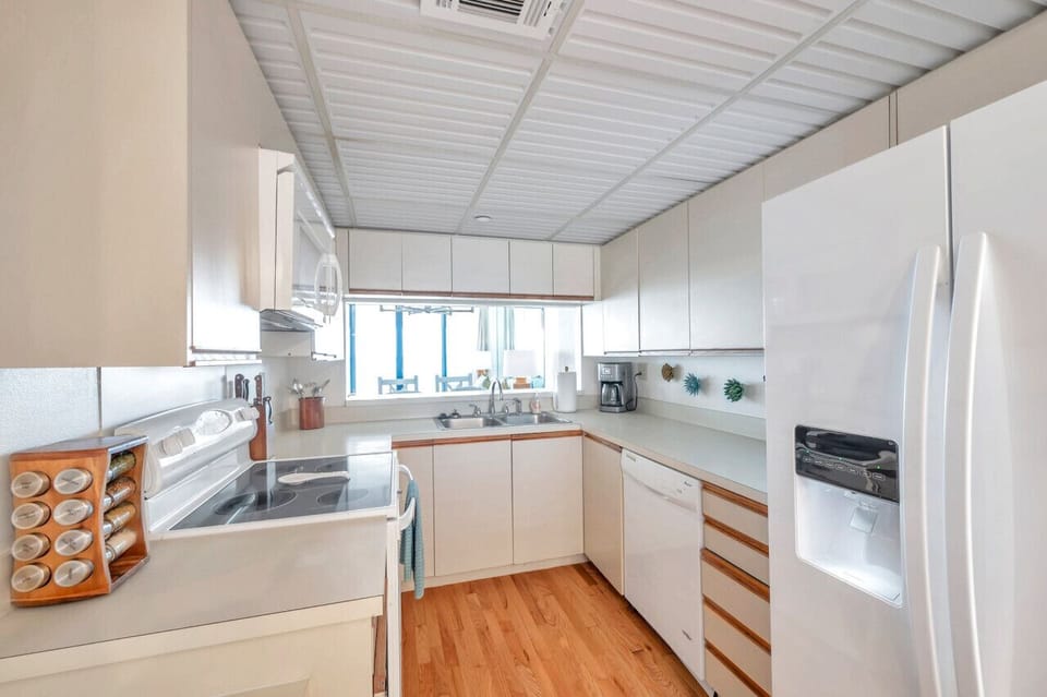 Sunlit kitchen w/ ample counter space & windows filling the room w/ light.