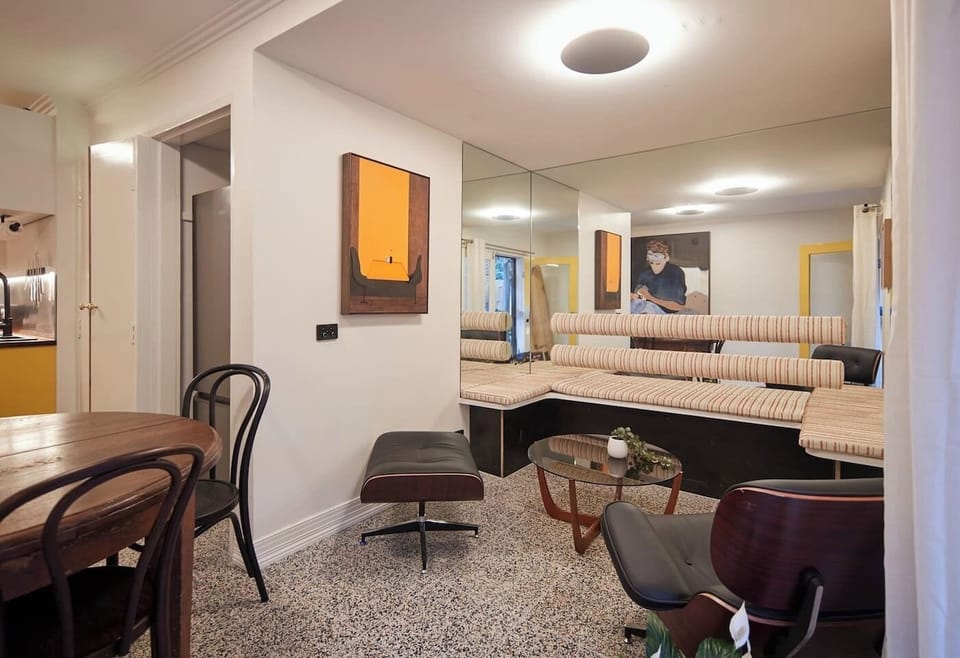 The living area is an architectural artwork with a mirrored lounge nook and a connected dining area accented with yellow pillars. 
