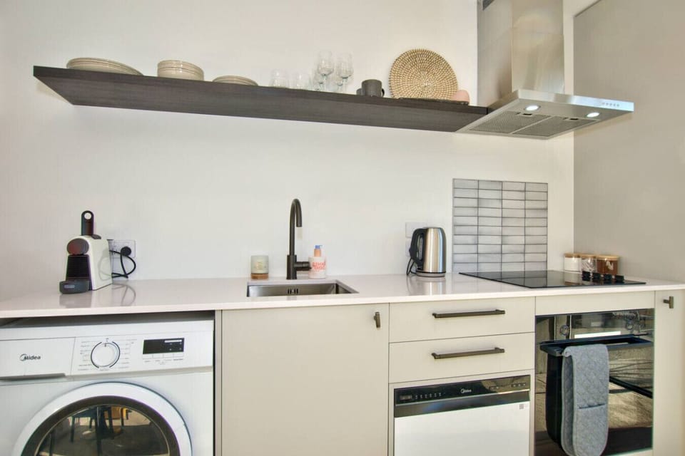 Kitchen with electric cooktop and stove, dishwasher, Nespresso coffee machine and washing machine.