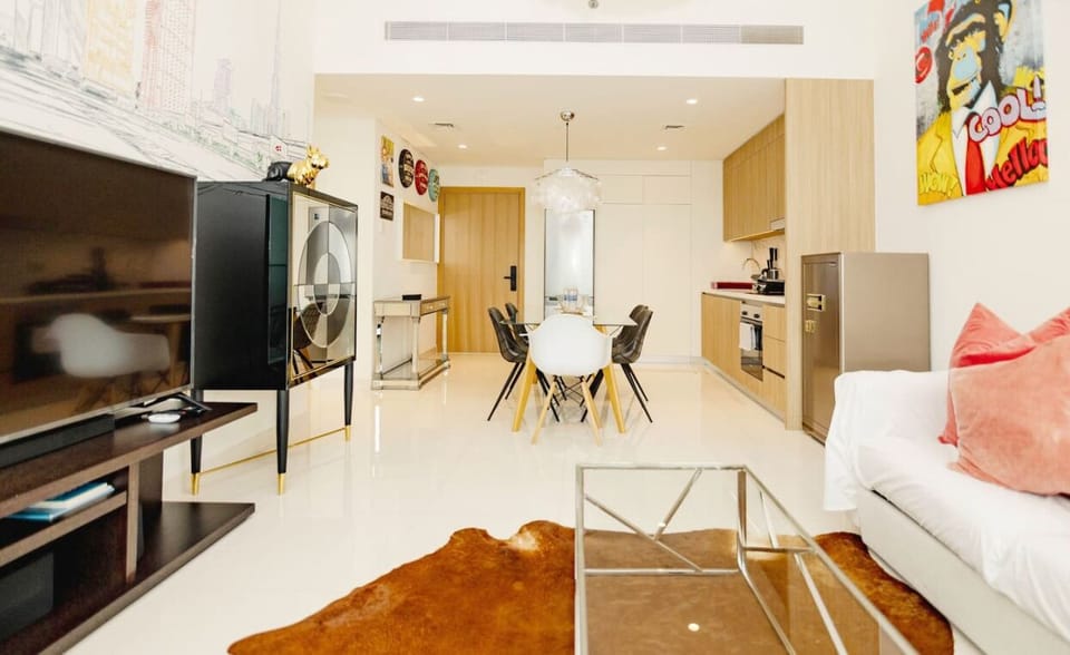 A well-lit living room with a glass coffee table, vibrant decor, and access to a balcony with outdoor seating.