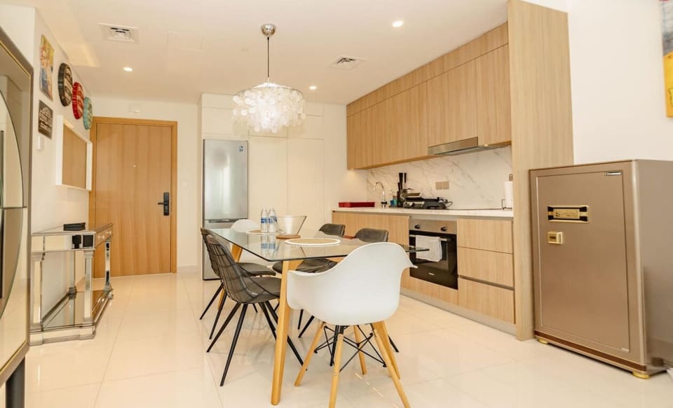 A sleek kitchen with wooden cabinetry and a connected dining area featuring a glass table and modern seating.