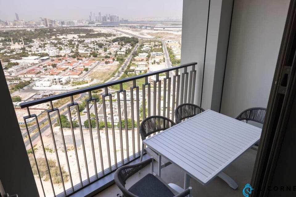 A small balcony with a table and two chairs, offering a view of the sprawling city and skyline.