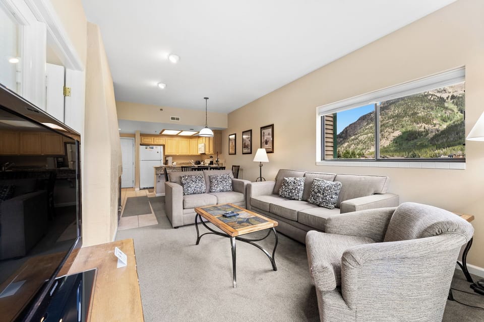Living area with large mounted flat screen TV, queen size sleeper sofa, wood-burning fireplace, and access to the private balcony.