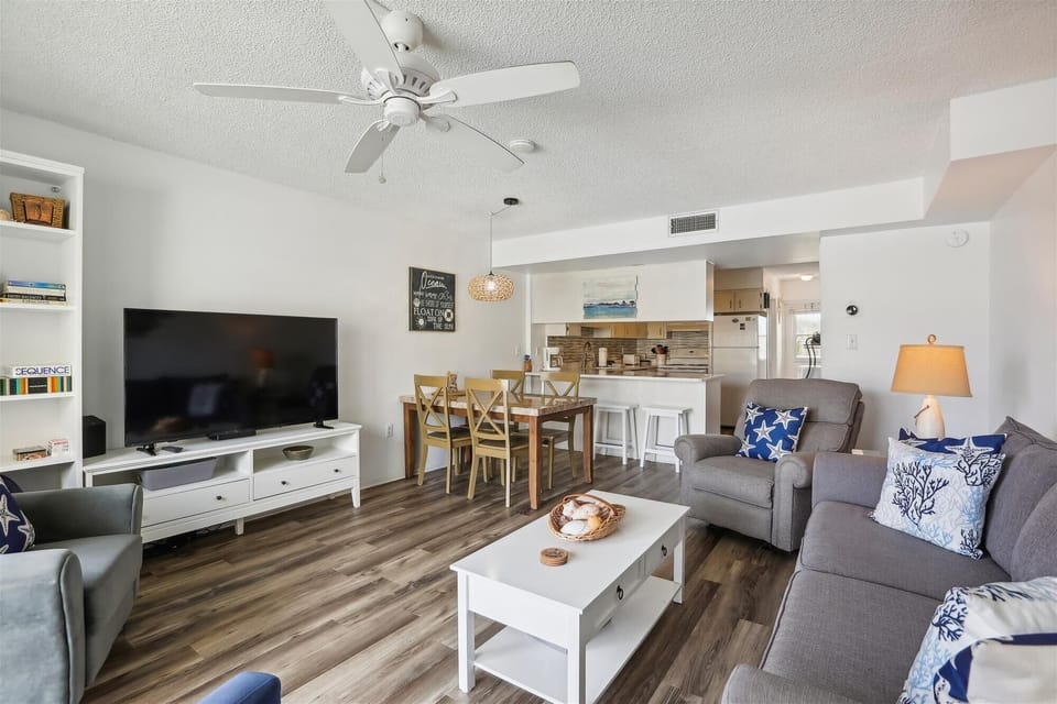 - Open layout living and dining space with modern beach decor  
- TV lounge area stylish furnishings and bright natural light  
- Family Airbnb rental close to beach pool and attractions  

