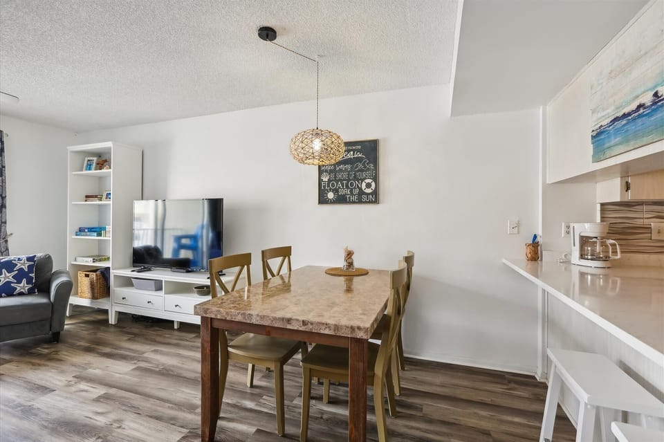 - Dining area with wood table coastal artwork and bright decor  
- Open concept near kitchen and living room creates easy flow  
- Airbnb beach rental with family friendly dining experience  

