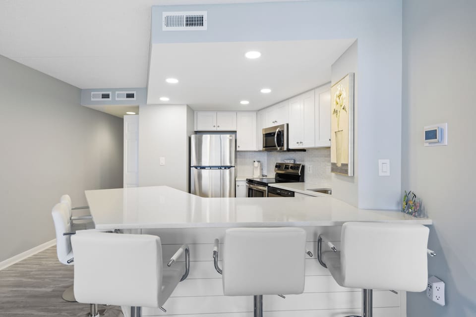 The bright white kitchen is modern and clean.