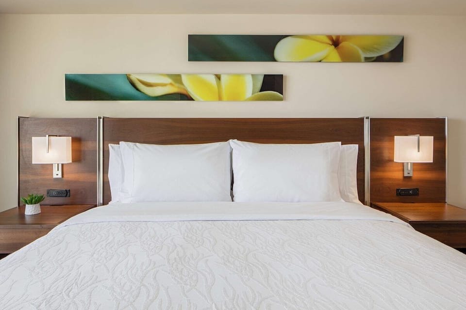 Sink into plush pillows beneath warm bedside glow and art.