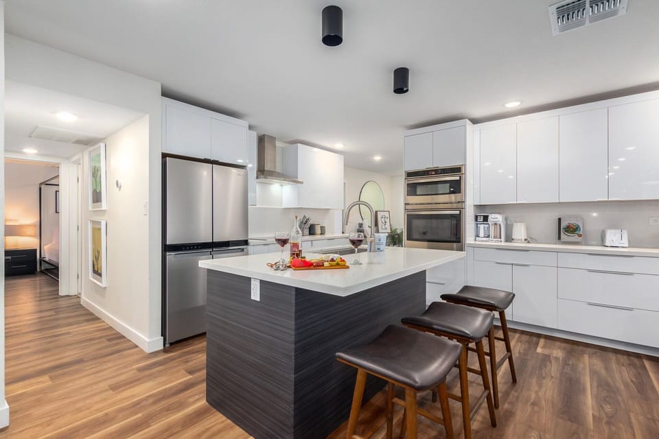 Elaborate kitchen with stainless steel appliances and a kitchen island with bar seating for 3 guests.