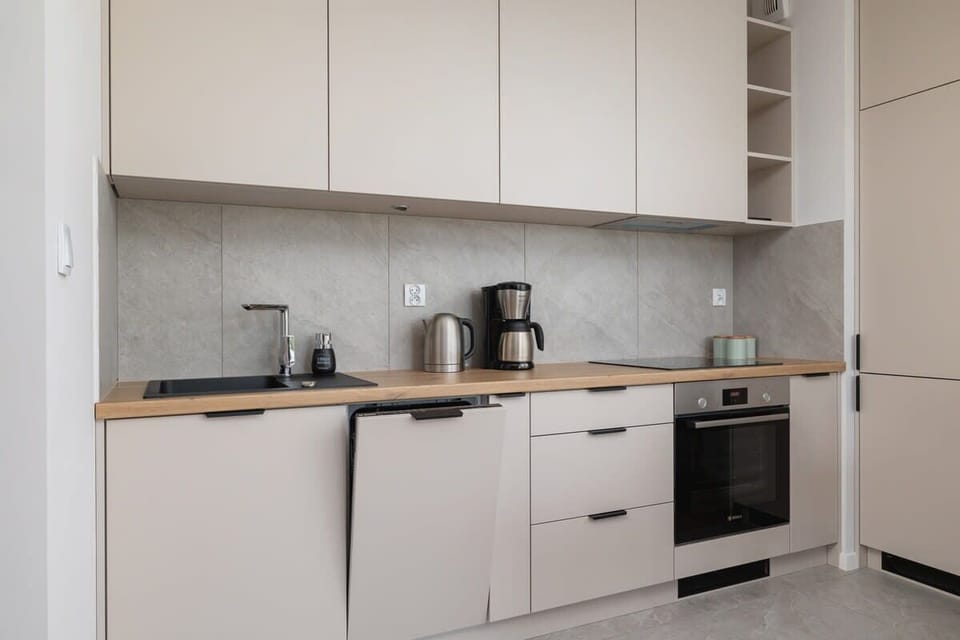 Sleek white kitchen with built-in appliances, coffee corner, and plenty of countertop space.