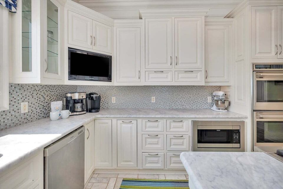 White kitchen with mosaic backsplash and stainless appliances