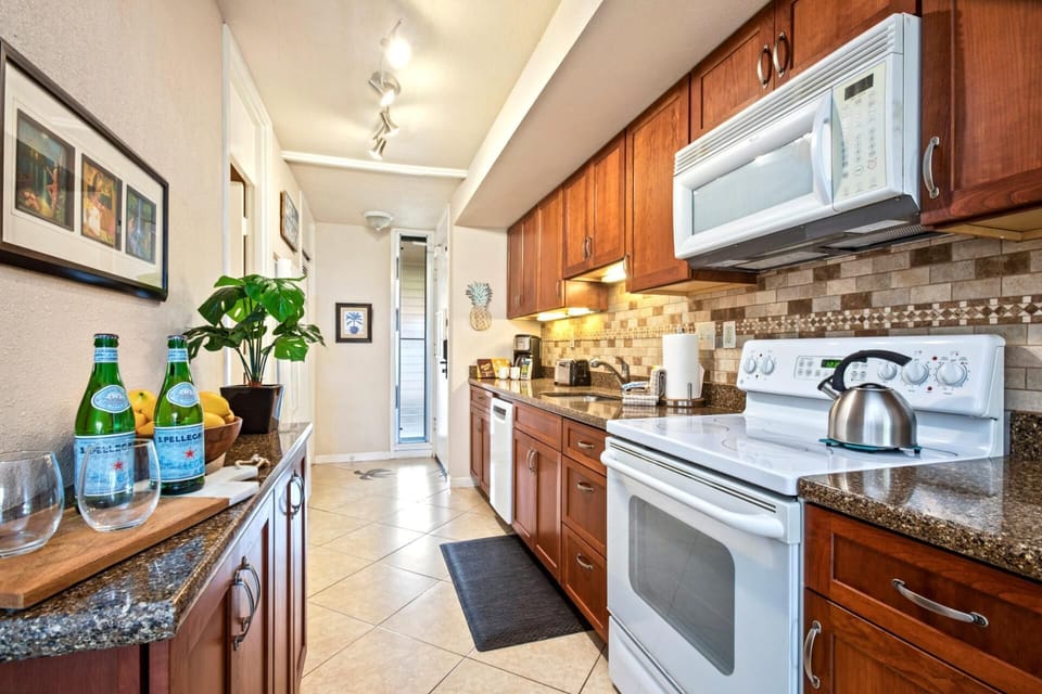 A galley of joy—this warm kitchen sparkles with cherry cabinets, mosaic tile, and a hint of tropical mischief    