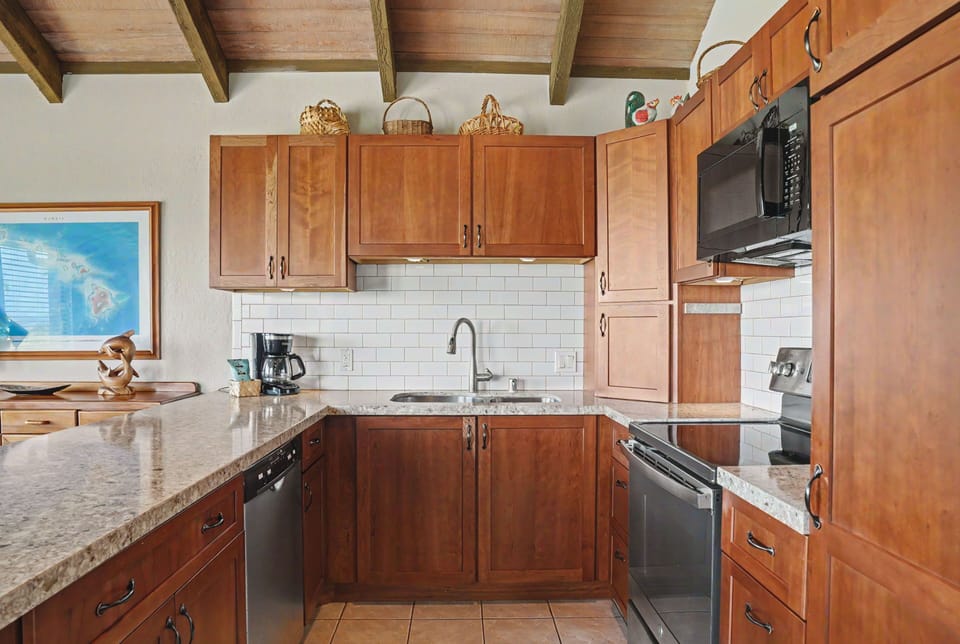 Your fully equipped kitchen features granite countertops, stainless appliances, and warm wood cabinetry beneath beautiful exposed beam ceilings—everything you need for a delicious home-cooked meal.