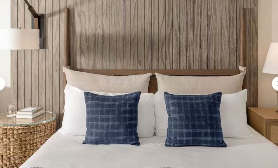 Sink into crisp linens beneath a warm, coastal headboard.