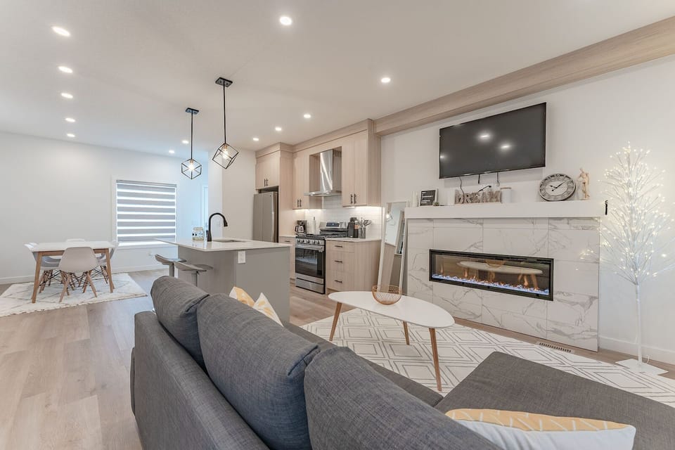 Open-concept with modern kitchen, cozy fireplace, and bright dining area.