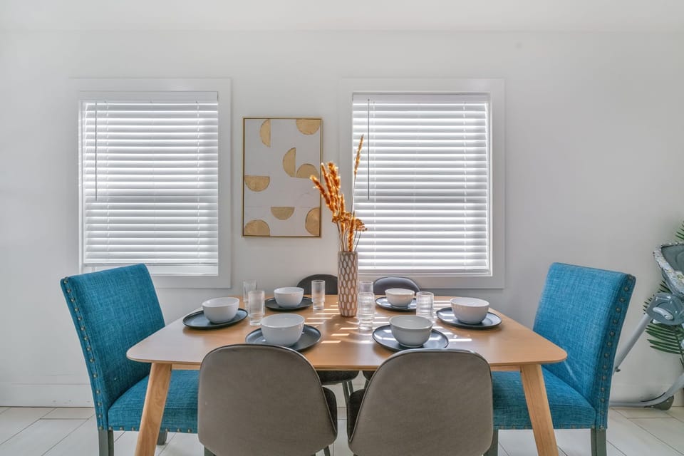 A modern, family dining with a sleek table, blue/gray chairs, and a highchair.