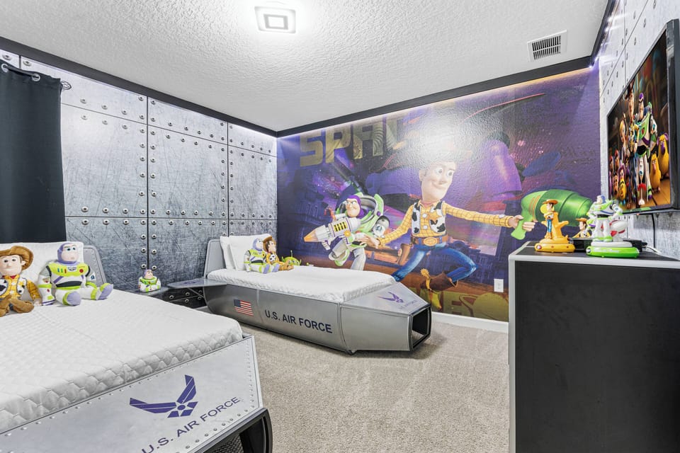 Step into this vibrant children's room, where playful decor meets comfort. The themed bedding, featuring beloved characters, complements the dynamic mural of space adventures, sparking imagination and fun for your little ones.