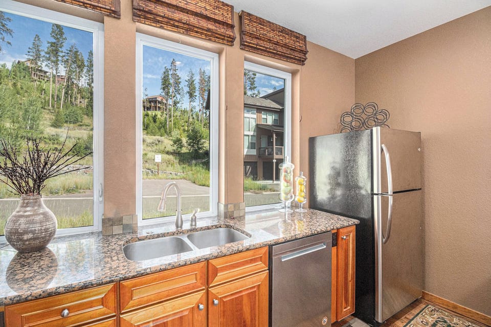 - Wash up while enjoying mountain views through three large picture windows
- Polished granite countertops and double basin sink offer everyday function
- Natural light and warm wood cabinetry give the kitchen an inviting glow