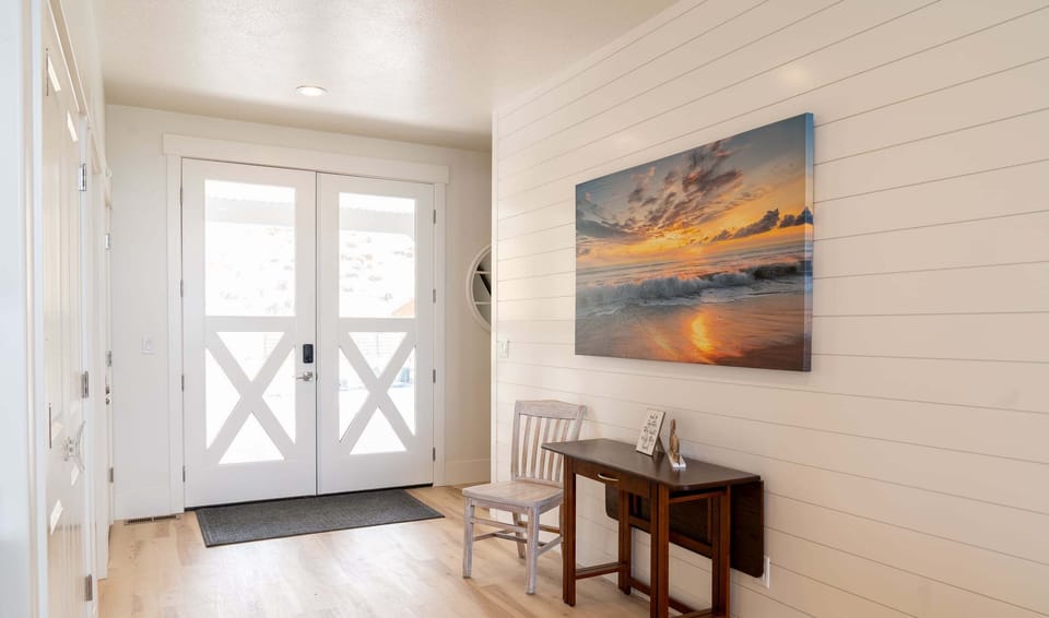 Front Entryway -- White doors, hall table, chair, stairs to upper floor.