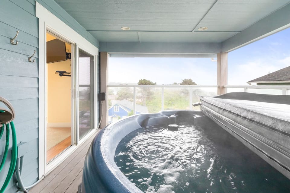 Hot tub on the covered upper balcony — coast views while you soak