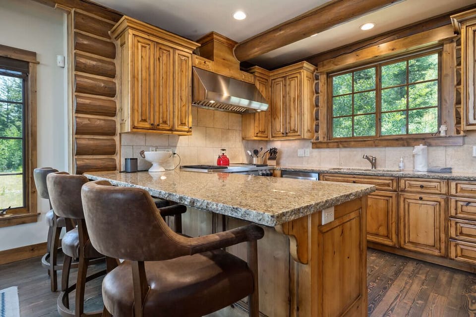 Cook and chat around the granite island with forest views.