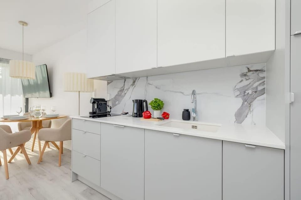 A compact, modern kitchen with white cabinetry and wooden accents. Fully equipped with everything needed to prepare a delicious meal.