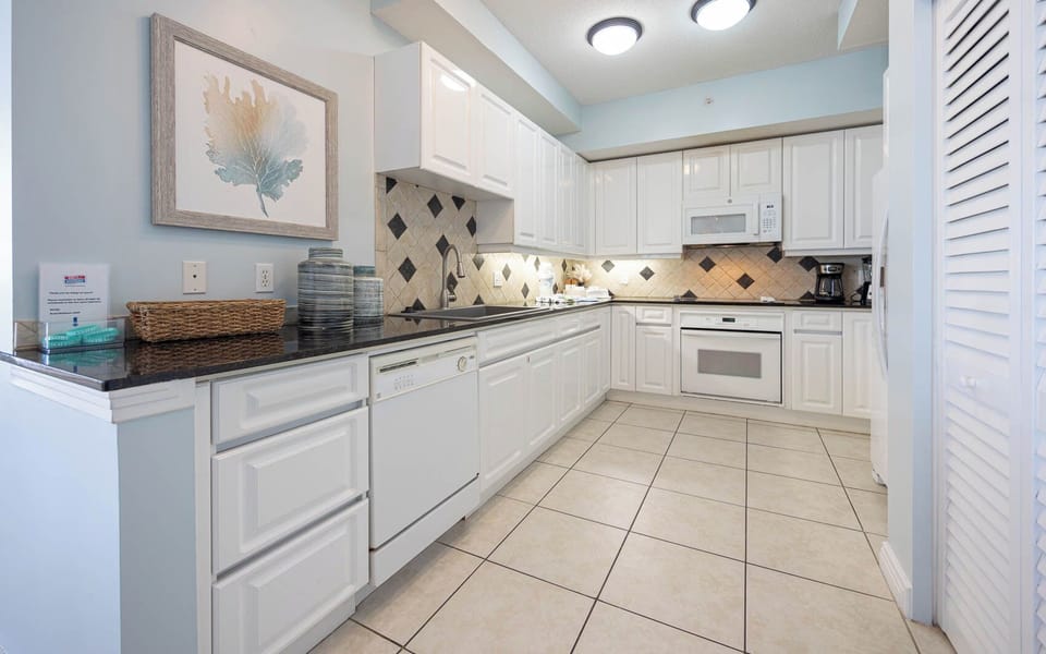 This kitchen features sleek white cabinetry, granite countertops, and a stylish backsplash, perfect for culinary adventures