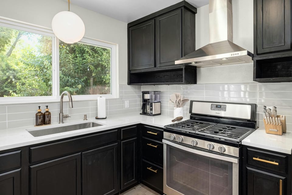 Enjoy our fully stocked kitchen with sleek black cabinets and pristine white quartz countertops that offer a modern, stylish space where you can easily prepare meals or grab a quick snack, with everything from pots and pans to useful appliances within reach. 