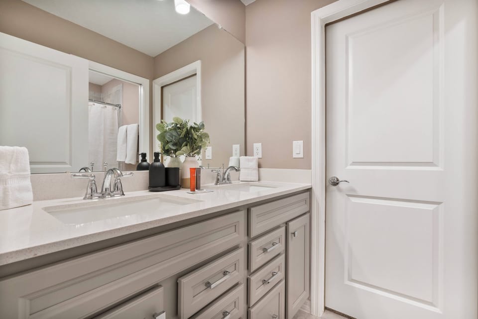 Bright and airy, this bathroom features a spacious double vanity with sleek cabinetry and elegant fixtures. Natural light floods in, enhancing the neutral tones and creating a refreshing atmosphere for your daily routines.