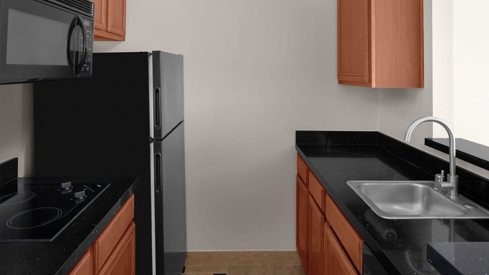 Prepare snacks with a sleek sink, microwave, and cooktop nearby.