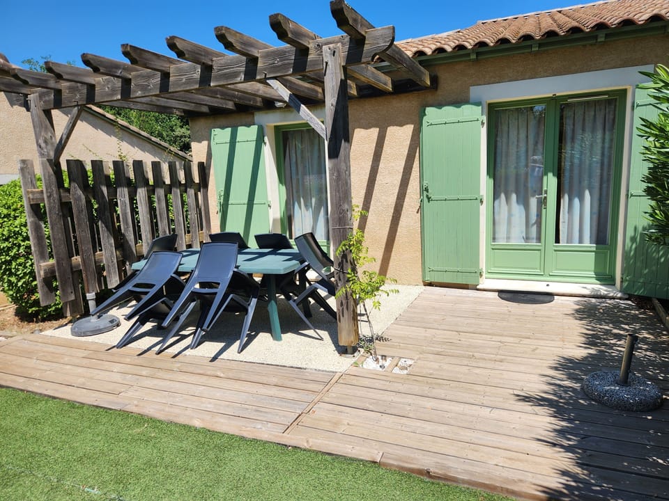 Gather around the outdoor dining table and black chairs, set beneath the pergola near the terrace.