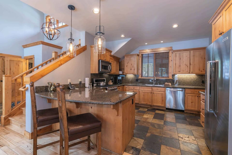 Kitchen features stainless steel appliances, granite countertops, and bar seating.