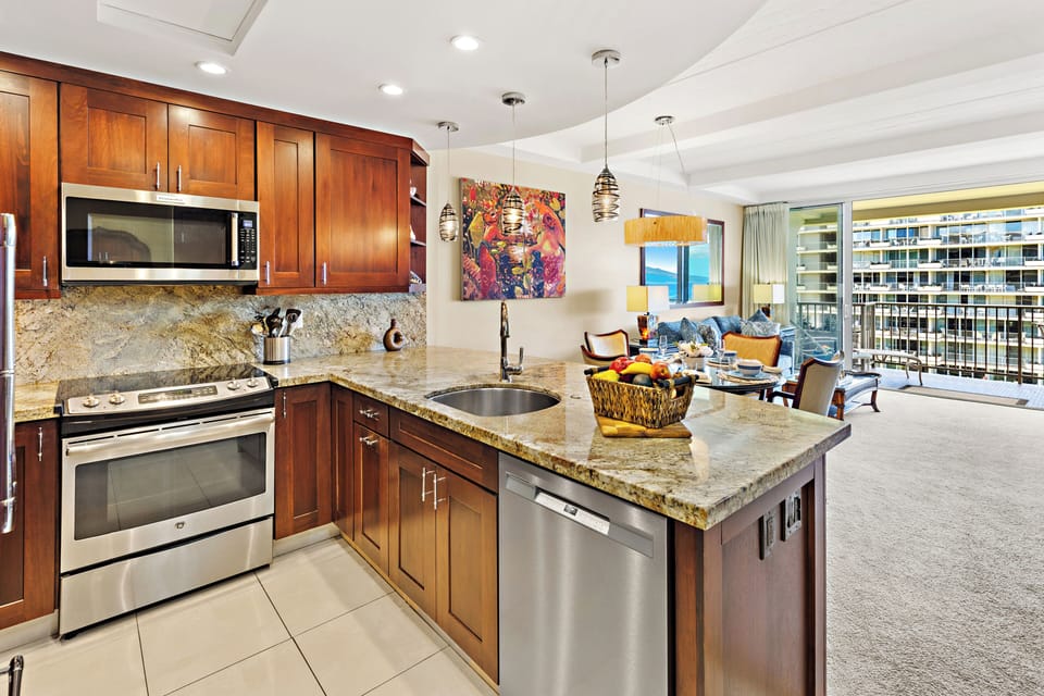 Well-appointed kitchen featuring rich wood cabinetry, granite countertops, and a central island with bar seating—seamlessly connected to the dining and living areas for a polished and inviting layout.