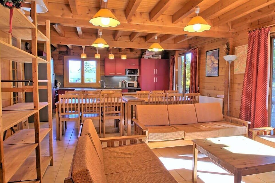 The open-plan living area boasts a spacious dining table with seating for a large group, ideal for enjoying meals together after a day of exploring the slopes. The cozy living area features a comfortable sofa and coffee table, perfect for relaxing and unw