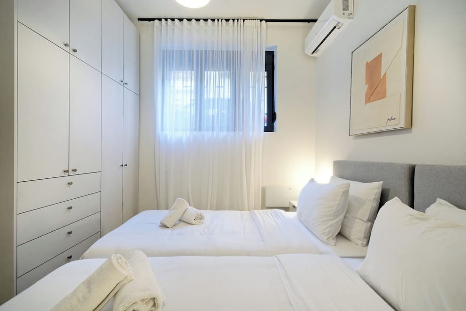 Bright twin bedroom with plush linens, soft lighting, and stylish artwork