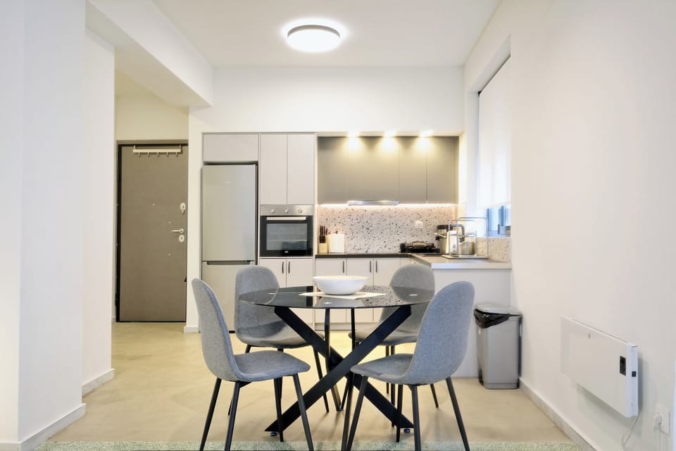 Dining area with natural light, sleek table, and cozy seating for four